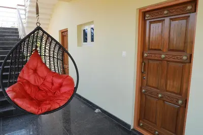 a red chair hanging from a porch swing at Maitree Serenity Farm Stay