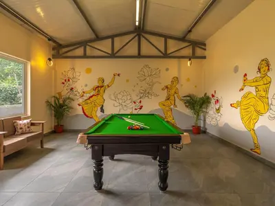 a pool table in a room with paintings on the wall at The Hosteller Kodaikanal in Kodaikānāl