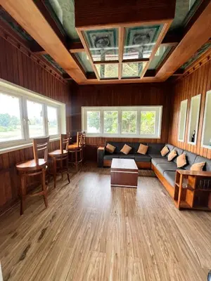 a living room with a couch and tables and windows at Riverside Luxury Private Pool Villa in Athirappilly in Athirappally