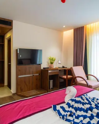 a hotel room with a bed and a tv and a desk at Senora Suites in Kannur