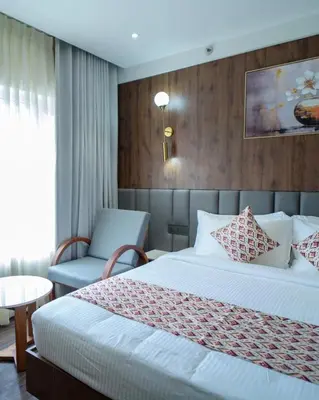 a hotel room with a bed and a chair at Senora Suites in Kannur
