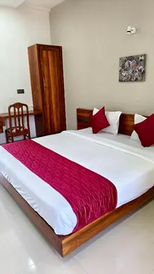 a bedroom with a large white bed with red pillows at Nelleri Residency Managed By Vaishno Hospitality in Iritti