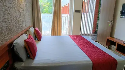 a bedroom with a bed with red pillows and a window at Nelleri Residency Managed By Vaishno Hospitality in Iritti