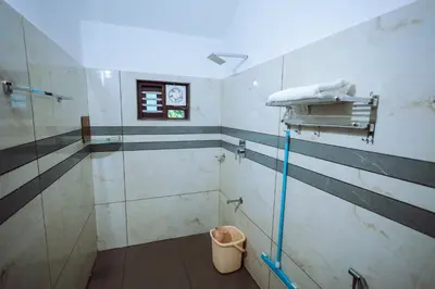a bathroom with a shower with a glass door at Wayanadan Huts Homestay in Sultan Bathery
