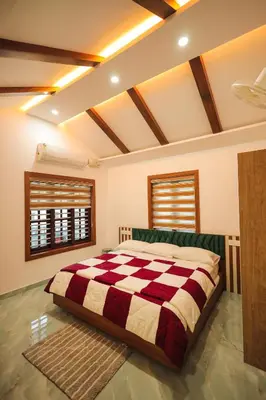 a bedroom with a large bed with a checkered blanket at Wayanadan Huts Homestay in Sultan Bathery