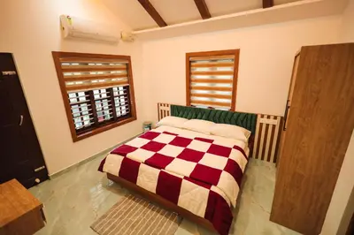a bedroom with a bed with a checkered blanket at Wayanadan Huts Homestay in Sultan Bathery