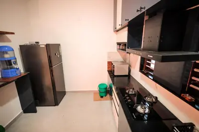 a kitchen with a stove and a refrigerator at Wayanadan Huts Homestay in Sultan Bathery