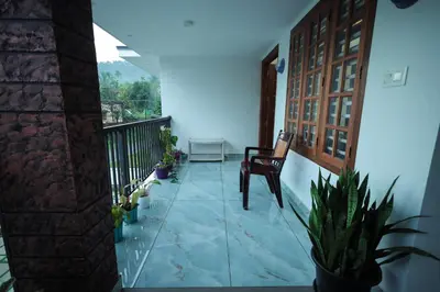 a room with a balcony with a chair and plants at Wayanadan Huts Homestay in Sultan Bathery