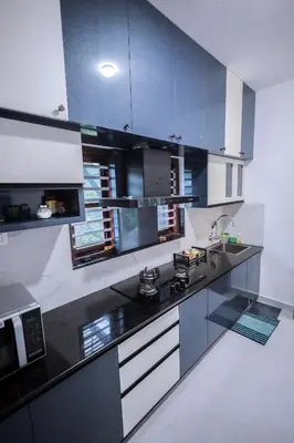 a kitchen with a black and white counter top at Wayanadan Huts Homestay in Sultan Bathery