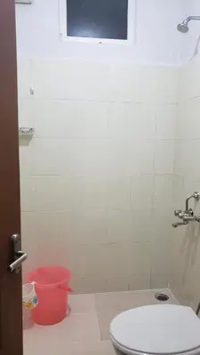 a bathroom with a toilet and a pink bucket at Cliff view in Ooty