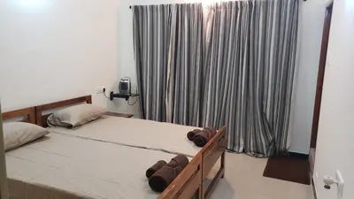 a bedroom with two beds and a window with curtains at Cliff view in Ooty