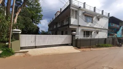 a white house with a fence in front of it at Cliff view in Ooty