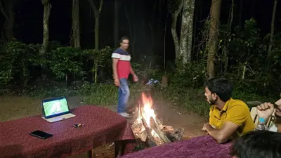 a woman standing in front of a camp fire at coorg Namana homestay in Suntikoppa