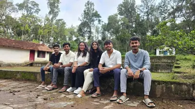 a group of people sitting on a stone wall at coorg Namana homestay in Suntikoppa