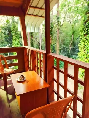 a room with a table and chairs on a balcony at coorg Namana homestay in Suntikoppa