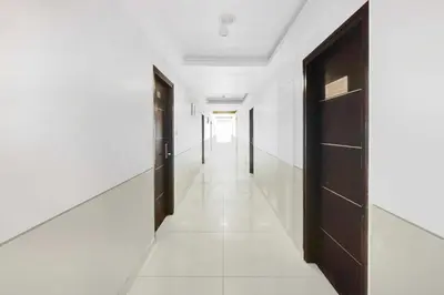 a hallway with black doors and white walls at Townhouse Oak Mysuru Railway Museum in Mysore