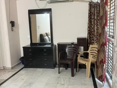 a room with a dresser and a mirror and chairs at City home-SGH in Mysore