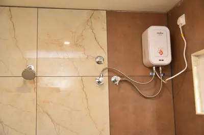 a shower with a soap dispenser on a wall at sree ganesh inn in Palani