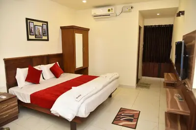 a bedroom with a large bed with red and white pillows at sree ganesh inn in Palani