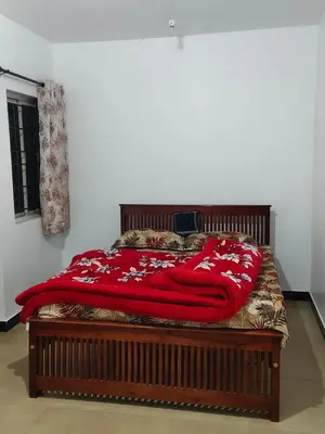 a bed with a red blanket on top of it at shambhala homestay in Ooty