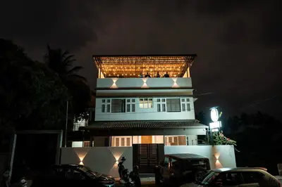 a tall white building with a balcony on top of it at Beach House in Kozhikode
