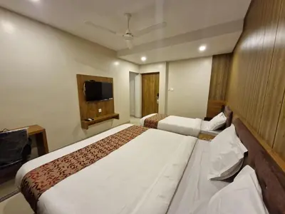 a hotel room with two beds and a flat screen tv at Le Royal Suite in Udumalaippettai