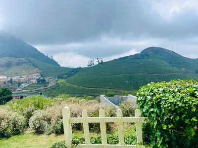 a bench sitting on a hill with mountains in the background at Away From Home - 1 - Home Stay Ooty, Entire 3BHK Villa in Ooty