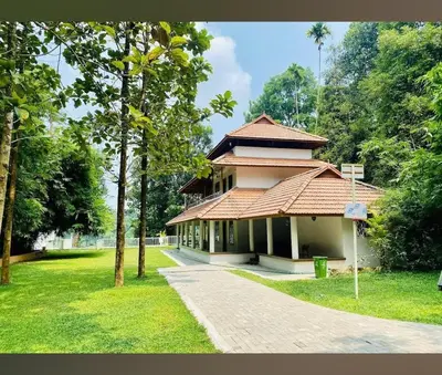 a building with a pathway in a park with trees at Enchanted Woods in Perumbavoor