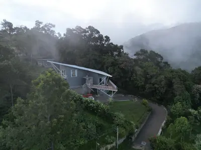 a house on the side of a hill with a road at Ibex Resorts, Coonoor - Tapas in Yedapalli