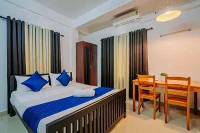 a bedroom with a bed and a desk and a table at Holiday Homes Aluva in Alwaye