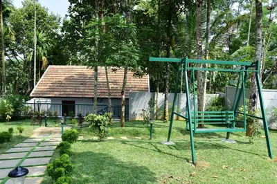 a swing in a yard with a house in the background at Snow White Wayanad in Wayanad