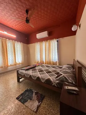a bedroom with a bed in a room with windows at Maryland homestay in Thattakād