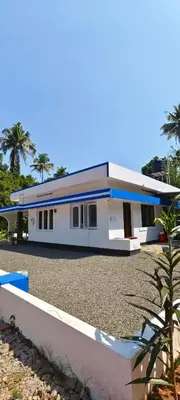 a large white building with palm trees in the background at Maryland homestay in Thattakād