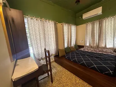 a bedroom with a bed and a window with curtains at Maryland homestay in Thattakād