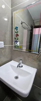 a bathroom with a white sink and a mirror at Premium Service apartment in Mysore