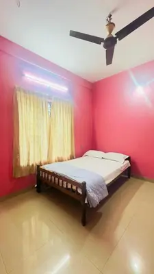 a bed in a room with a red wall at EV7 Stays in Trichūr