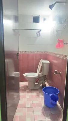 a bathroom with a toilet and a blue bucket at EV7 Stays in Trichūr