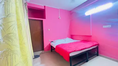 a pink room with a bed with a red blanket at EV7 Stays in Trichūr