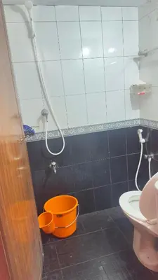 a bathroom with an orange bucket and a shower at EV7 Stays in Trichūr