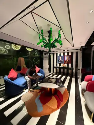 a man sitting on a couch in a living room at 2BR Flat with Pool and Balcony near Cochin Airport in Cochin