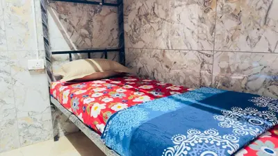 a small bed with a red and blue blanket at Mysuru dorm-sgh in Mysore