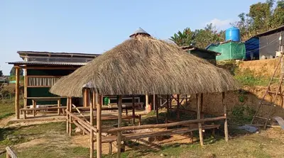 a hut with a straw roof and benches in front at Muffintrip stays camp N trek in Kūkkāl