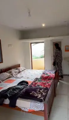 a woman standing next to two beds in a room at Muffintrip stays camp N trek in Kūkkāl