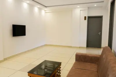 a living room with a couch and a tv on a wall at Nestora Suites in Kozhikode
