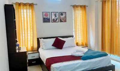 a small bedroom with a bed with orange curtains at Nestora Suites in Kozhikode