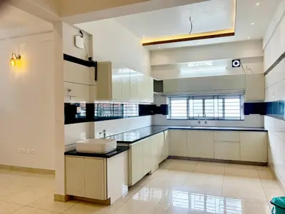 a large kitchen with white cabinets and a sink at Nestora Suites in Kozhikode