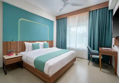 a bedroom with a large bed with a desk and a window at REGAL HEIGHTS in Ernakulam