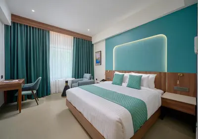 a bedroom with a large bed with a blue wall at REGAL HEIGHTS in Ernakulam