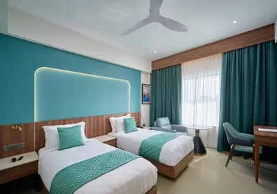 a hotel room with two beds and a desk at REGAL HEIGHTS in Ernakulam