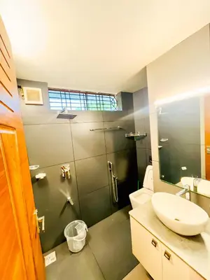 a bathroom with a shower with a sink and a toilet at Executive Room in Kelakam